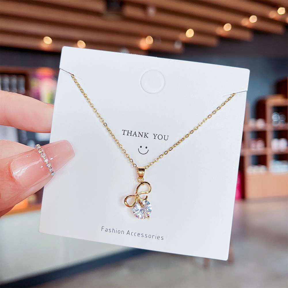 Kalung Rantai Dengan Liontin Pita Bahan Titanium Steel Aksen Batu Zircon Untuk Wanita