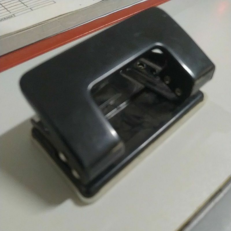 

Pembolong kertas warna hitam.