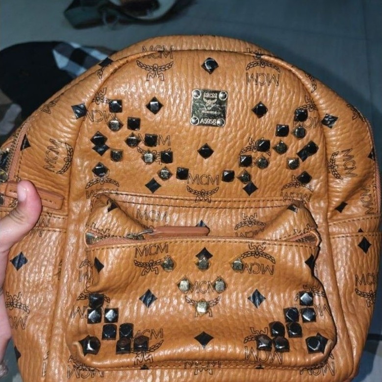Tas Ransel MCM warna cokelat motif stempel dengan aksen paku hitam model backpack