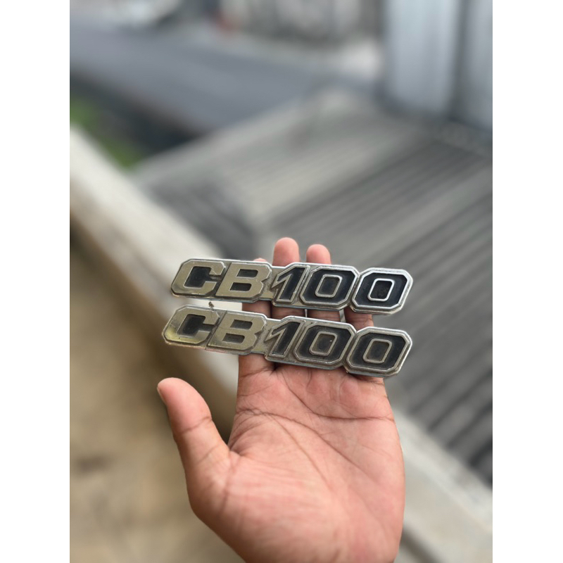 EMBLEM TUTUP AKI CB100 K5 ORIGINAl