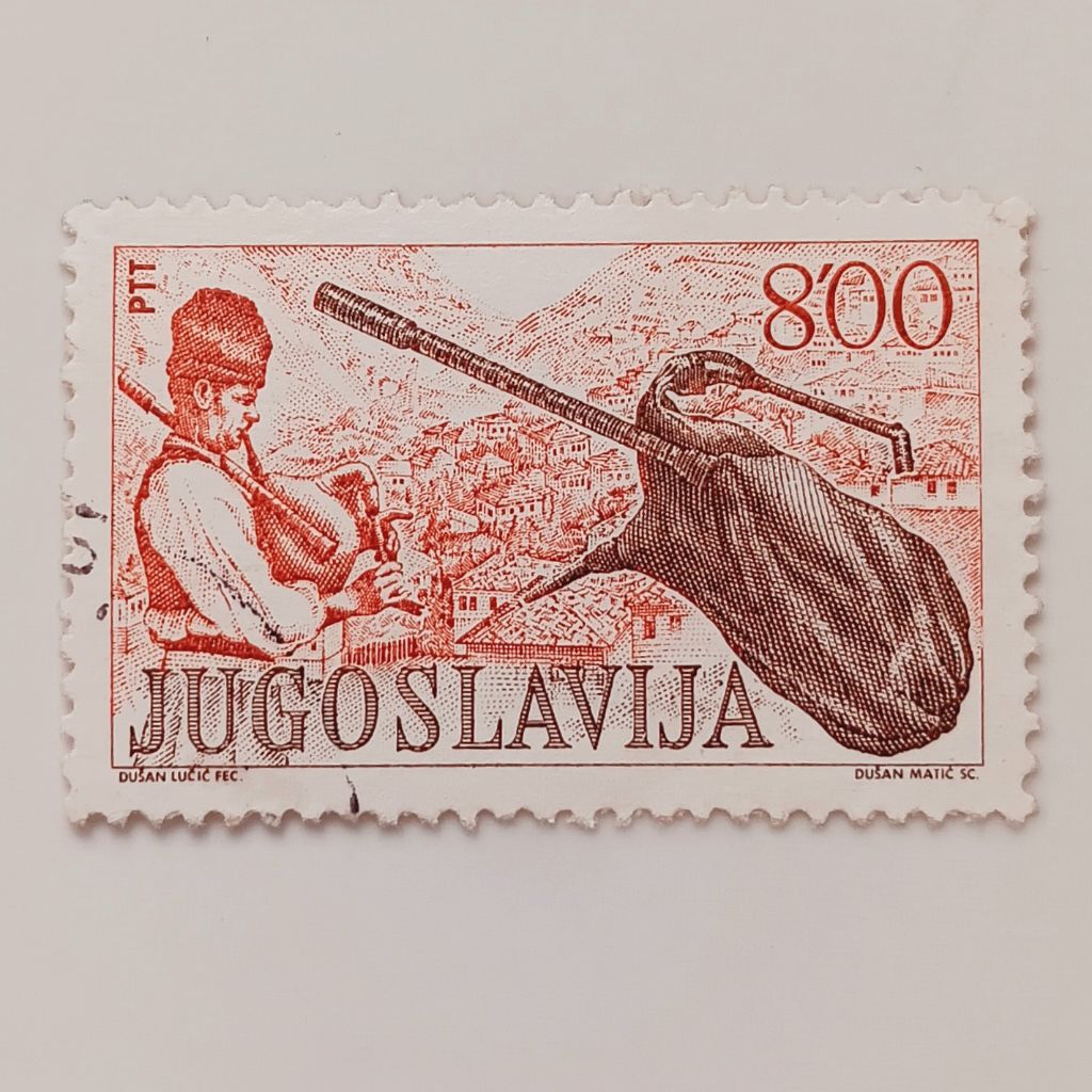 

(AA) Perangko Yugoslavia 1977 Museum Exhibits: Folk Music Instruments - Bagpipes, Mountain Town 8 dinar Used