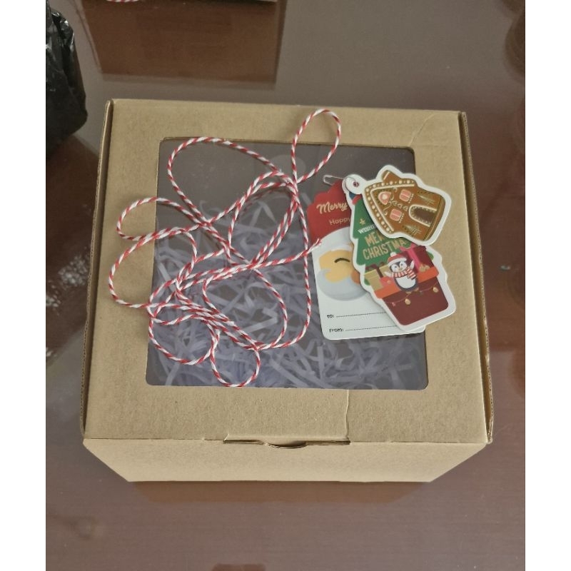 

Kotak dus berikut kartu ucapan dan tali hias kado bertema Natal