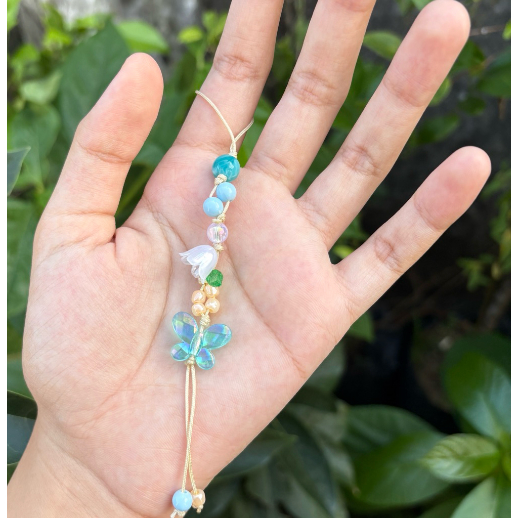 phone charm kupu biru dengan bunga bunga mengantung