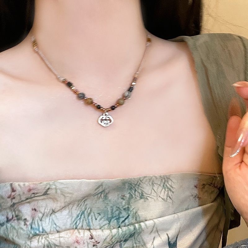 Kalung Tali Halus dengan Susunan Manik Warna Keemasan dan Hitam Putih serta Liontin Bunga Berukir
