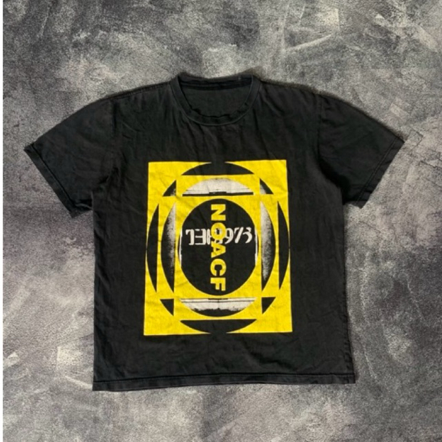 Tshirt NOACF" dari band The 1975, yang merujuk pada album mereka "Notes On A Conditional Form" (NOAC