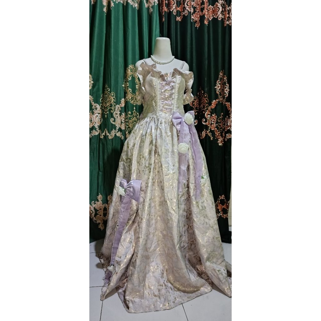 Gaun pesta warna ungu dengan aksesoris bunga