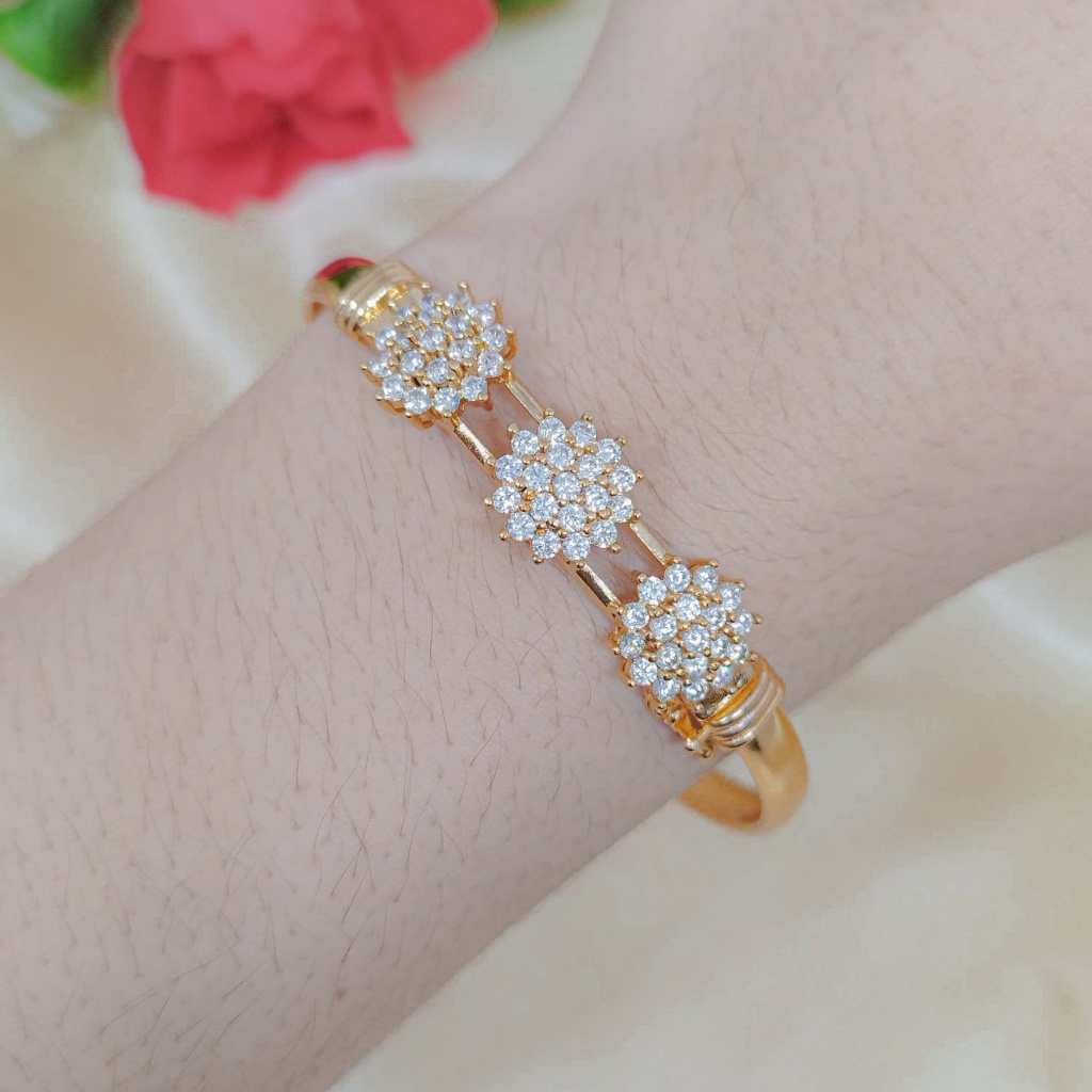 Gelang bangle terbuka berlapis emas 24 karat, dihiasi sepenuhnya dengan batu permata imitasi.