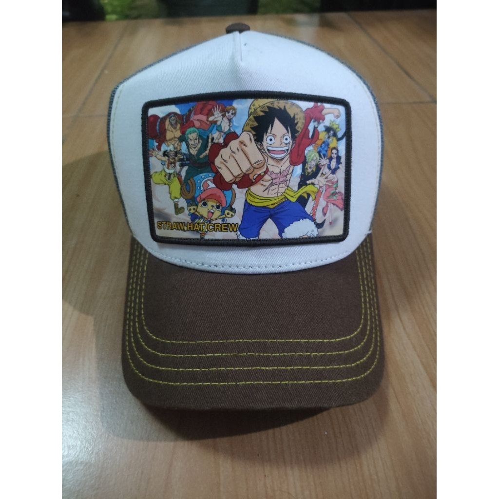 Topi ORIGINAL Trucker Capslab One Piece Straw Hat Crew berwarna cokelat dan putih.