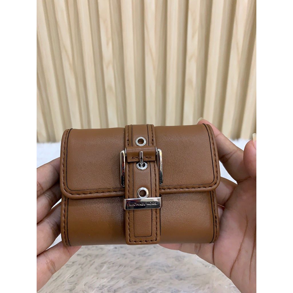 Dompet atau kecil tas tangan dari merek Michael Kors, yang ditunjukkan oleh logo tulisan "MICHAEL KO
