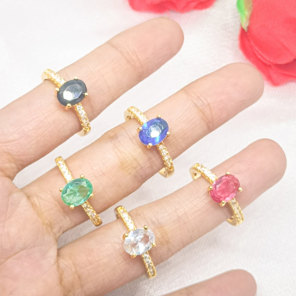 Cincin berlapis emas 24 karat dengan desain bulat, dihiasi dengan batu permata besar dan dikelilingi