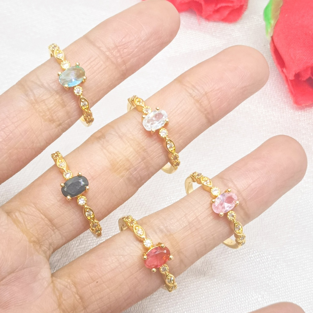 Cincin berlapis emas 24 karat dengan desain bulat, dihiasi dengan batu permata besar dan dikelilingi