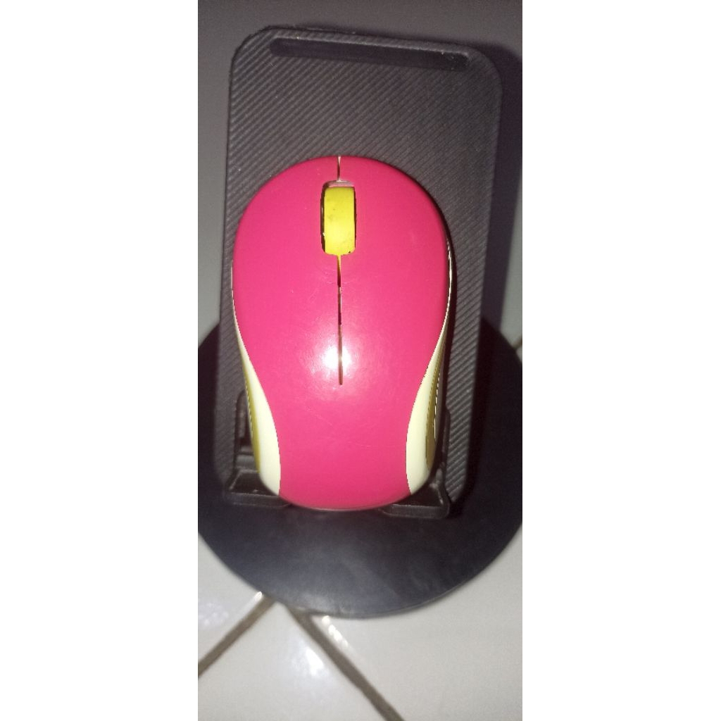 Logitech M187 Mini Wireless Mouse berwarna merah muda dengan aksen kuning.