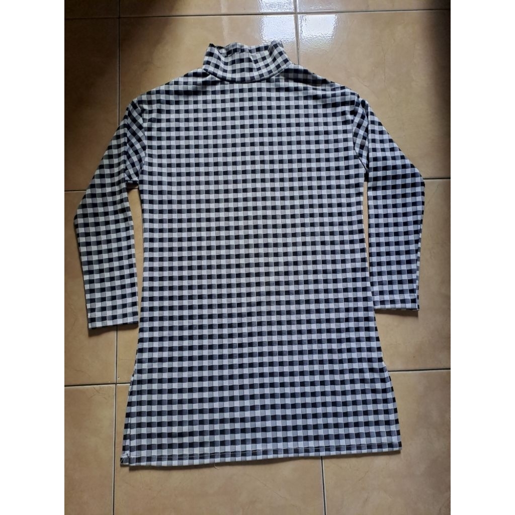 Atasan tunik lengan panjang motif kotak-kotak hitam putih dengan kerah tinggi (turtleneck).