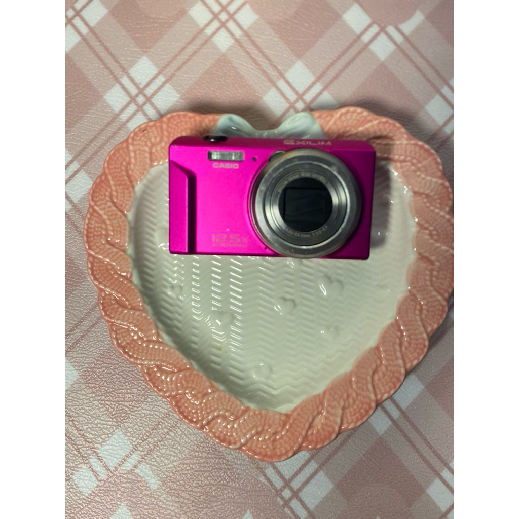 Casio Exilim EX-ZS150 berwarna merah muda terang.