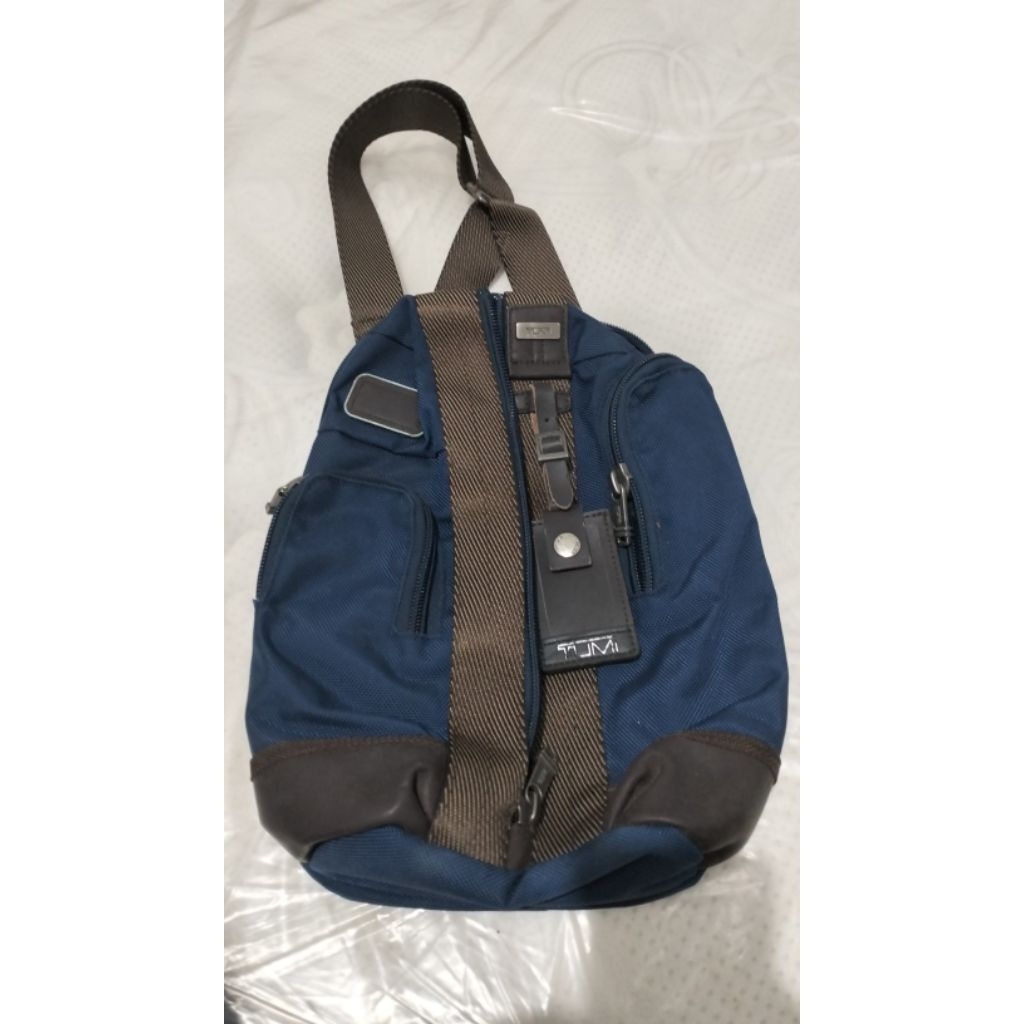 tas ini terlihat seperti TUMI sling bag/body bag berbahan balistik nylon warna biru dengan trim kuli
