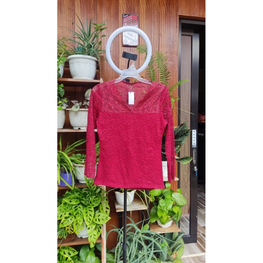 atasan brukat berwarna merah maroon (atau merah tua) dengan desain yang elegan dan feminim