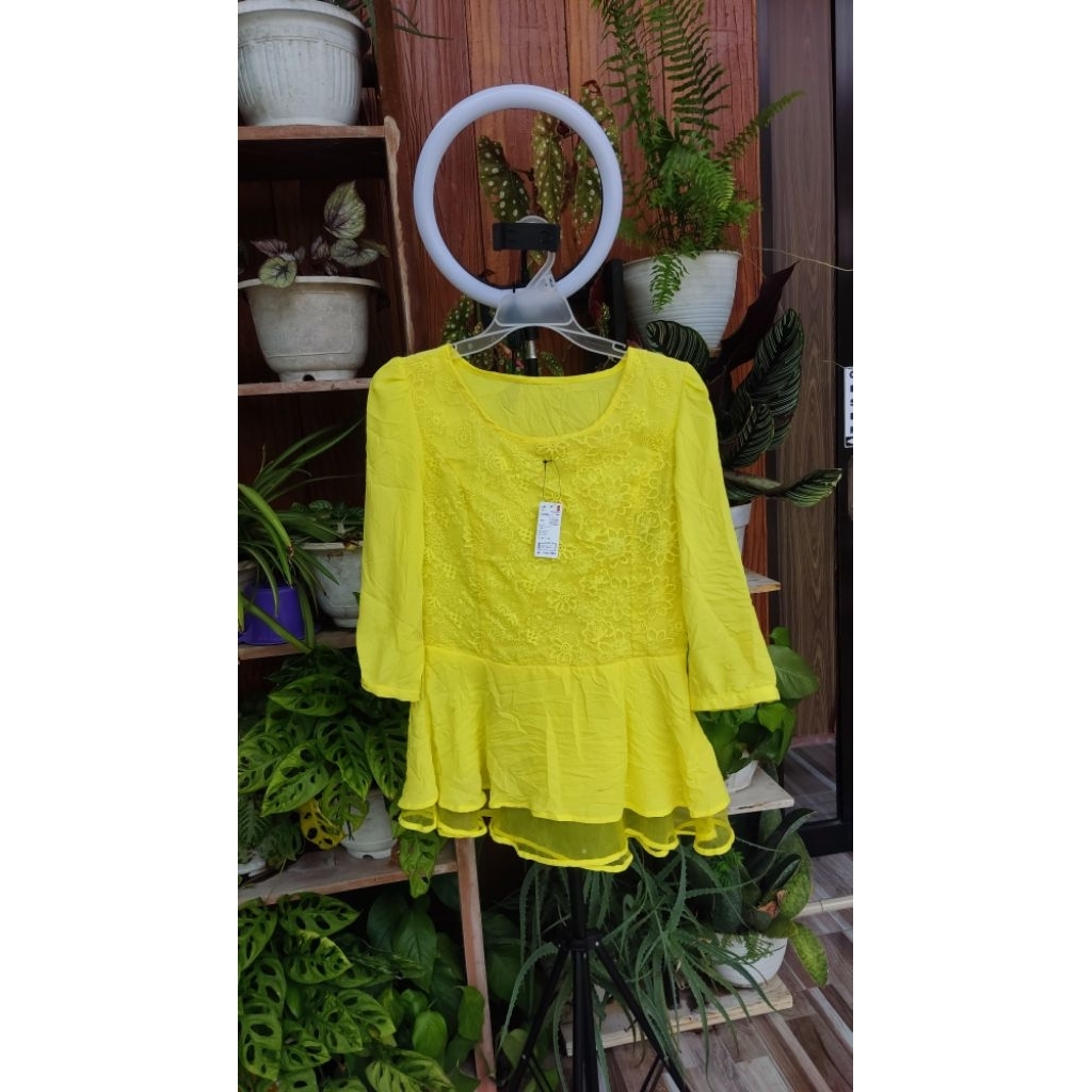 atasan kebaya modern atau blus berwarna kuning terang (lemon) yang terbuat dari bahan brokat dengan 