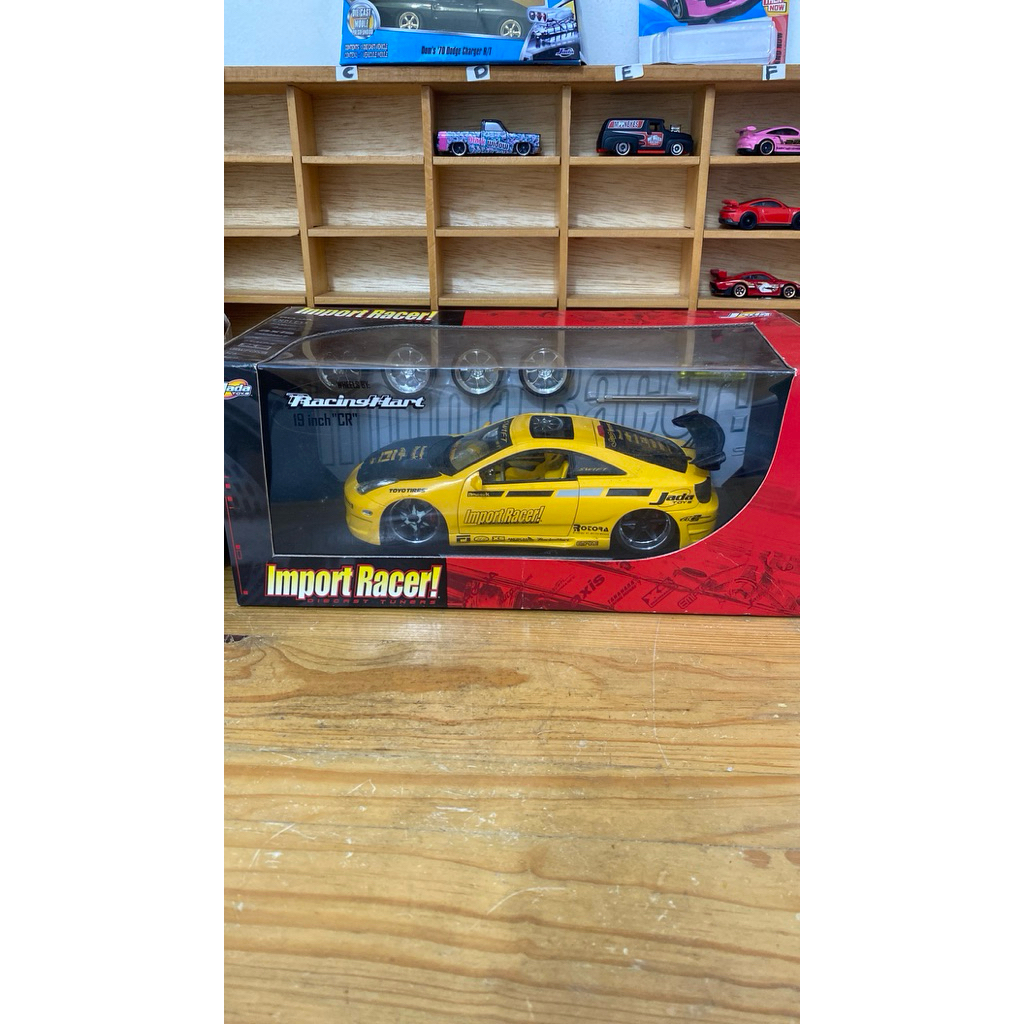 Jada Toys Import Racer skala 1:18 berbentuk Toyota Celica berwarna kuning.