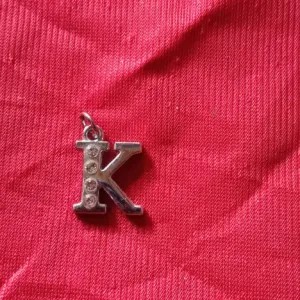 liontin putih huruf K