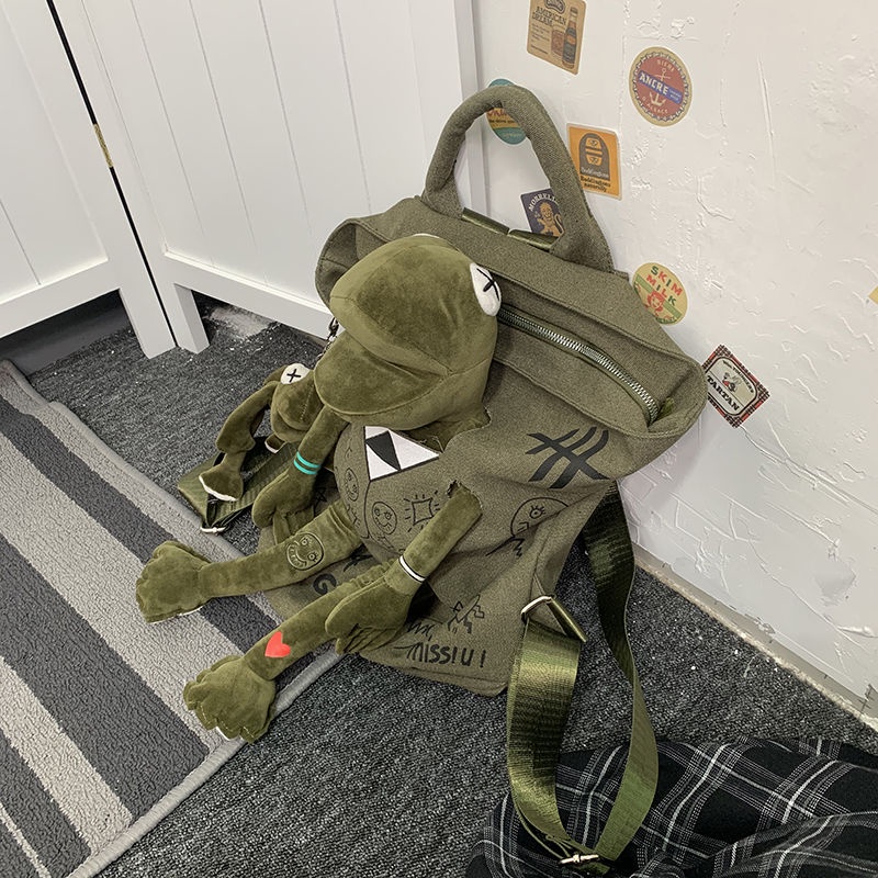 ✘♘✆Sera Jepang Street Cool Graffiti Seri Ransel Kanvas Gaya Hong Kong Sastra Katak Merek Tas Sekolah Boneka