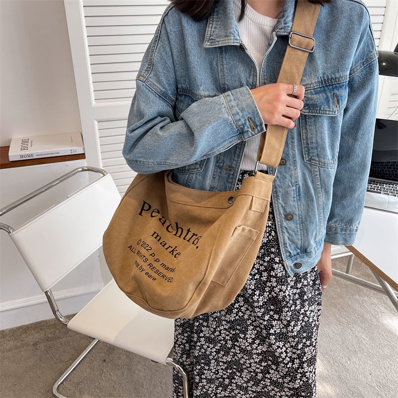 Sera import tas slempang fashion cewek tas wanita selempang bahan kanvas tas wanita selempang lebar elizabethTas Besar Gaya Mahasiswa Kelas Messenger Tas Baru Huruf Jepang Tas Kain All-Match Tas Bahu Tide