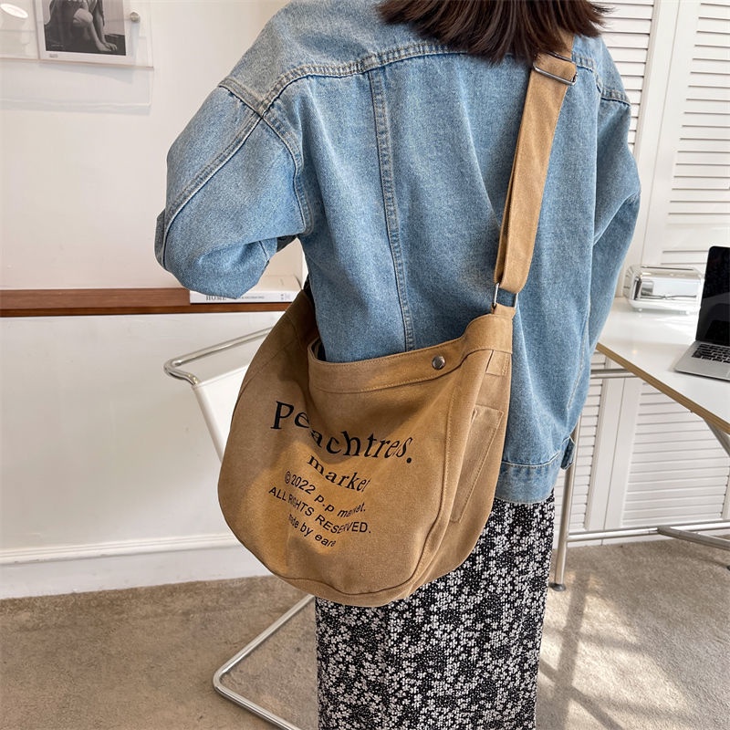 Sera import tas slempang fashion cewek tas wanita selempang bahan kanvas tas wanita selempang lebar elizabethTas Besar Gaya Mahasiswa Kelas Messenger Tas Baru Huruf Jepang Tas Kain All-Match Tas Bahu Tide