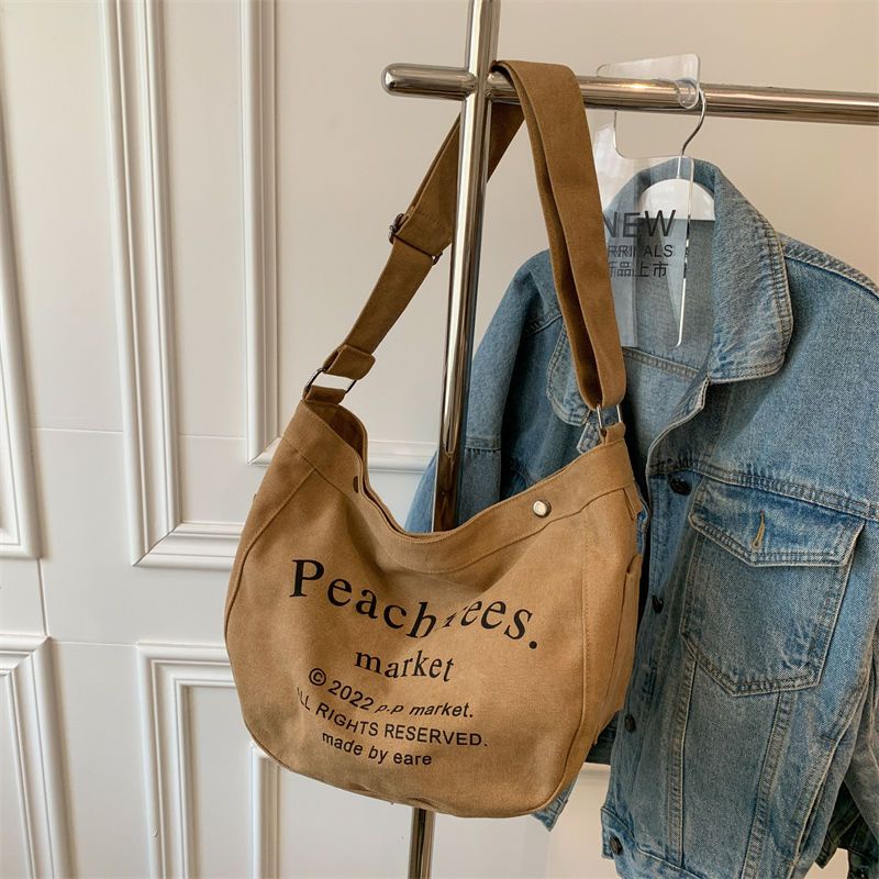 Sera import tas slempang fashion cewek tas wanita selempang bahan kanvas tas wanita selempang lebar elizabethTas Besar Gaya Mahasiswa Kelas Messenger Tas Baru Huruf Jepang Tas Kain All-Match Tas Bahu Tide