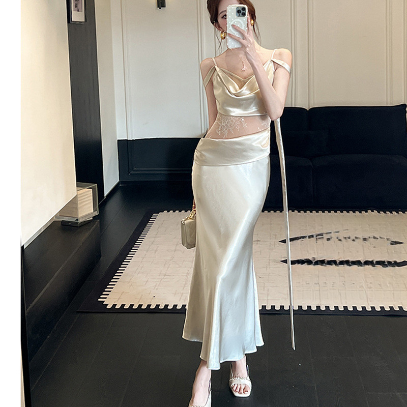 Mode Vogue Gaun wanita bertali spaghetti dengan hiasan renda, leher bulat, dan kain satin berkerut.