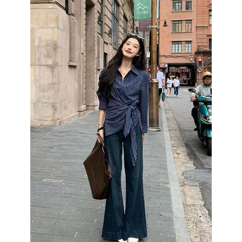 Kemeja bergaris biru tua bergaya Prancis untuk wanita, pas badan dan lengan panjang.