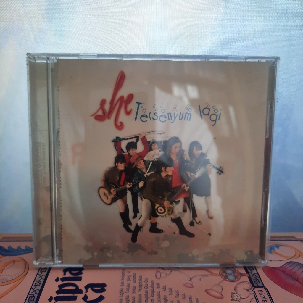 CD SHE- Tersenyum Lagi Original