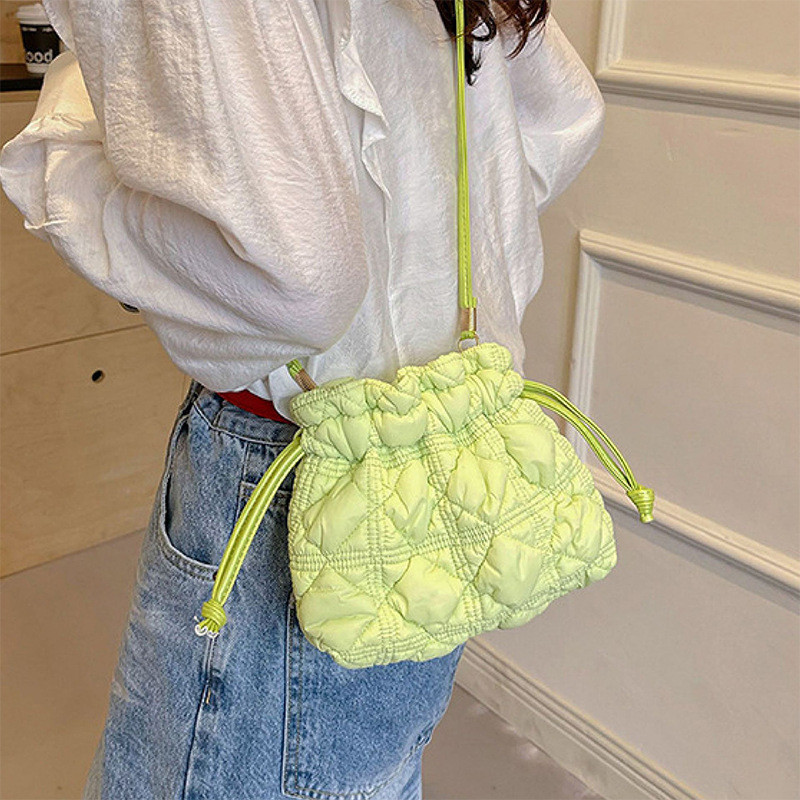 Tas selempang wanita model bucket dengan tali serut dan lipatan, terbuat dari kain lembut.