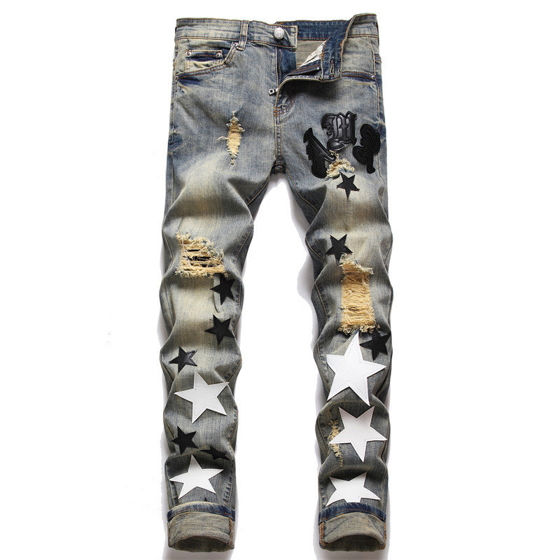 Celana jeans skinny pria yang robek dan ditambal dengan bintang kulit hitam putih yang bersulam.