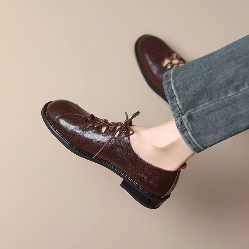 Sepatu kulit vintage berlubang dengan tali, hak rendah, ujung bulat model Mary Jane.